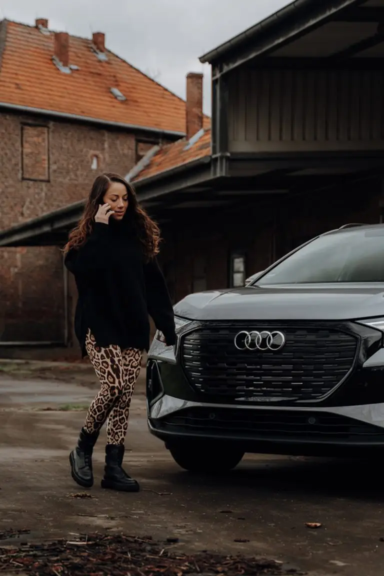 Frau an Telefon vor Audi